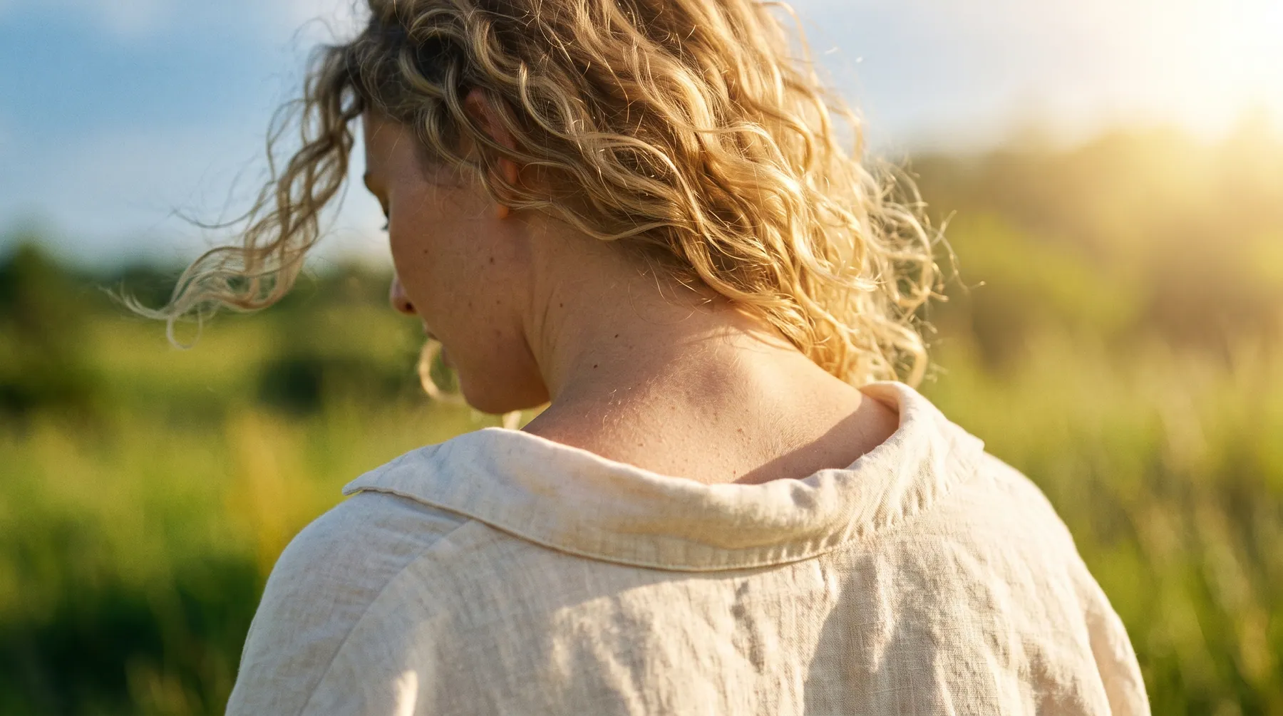 Schultern einer Frau im warmen Gegenlicht beim Ausatmen, Haare im Wind