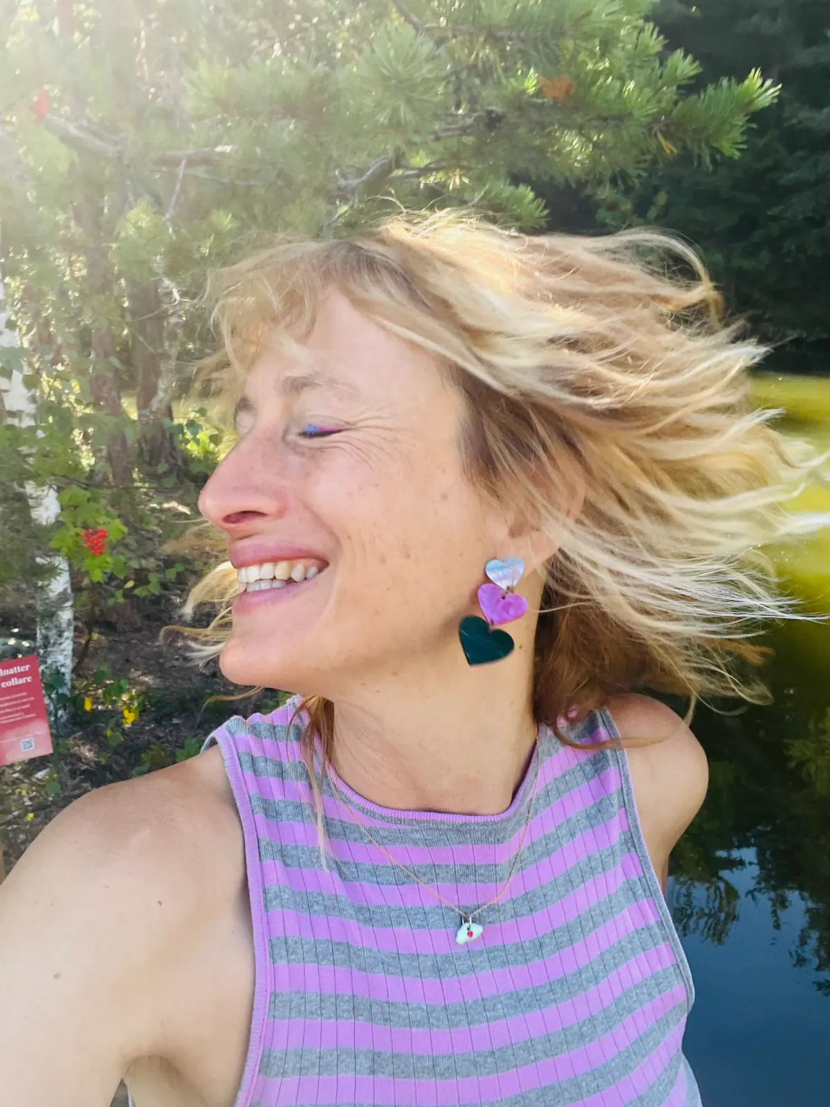 Johanna Mölk lacht, die Haare im Wind, vor Bäumen am Wasser